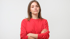 Frau mit verschränkten Armen und skeptischen Blick
