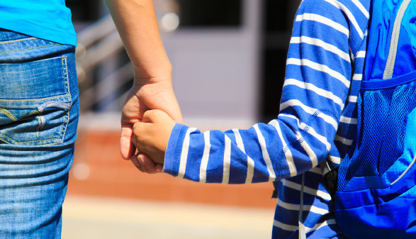 Mutter hält ihren Schulanfänger an der Hand