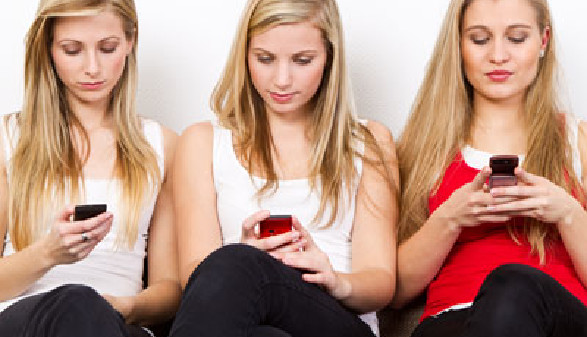 Drei junge Frauen spielen sorglos mit ihren Handys