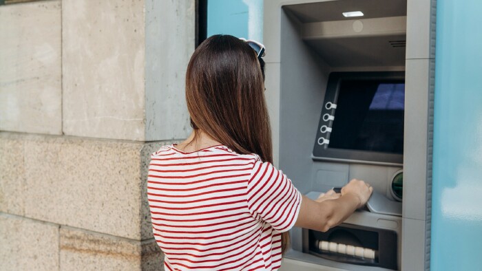 © franz12, stock.adobe.com Junge Frau hebt beim Bankomaten Geld ab.